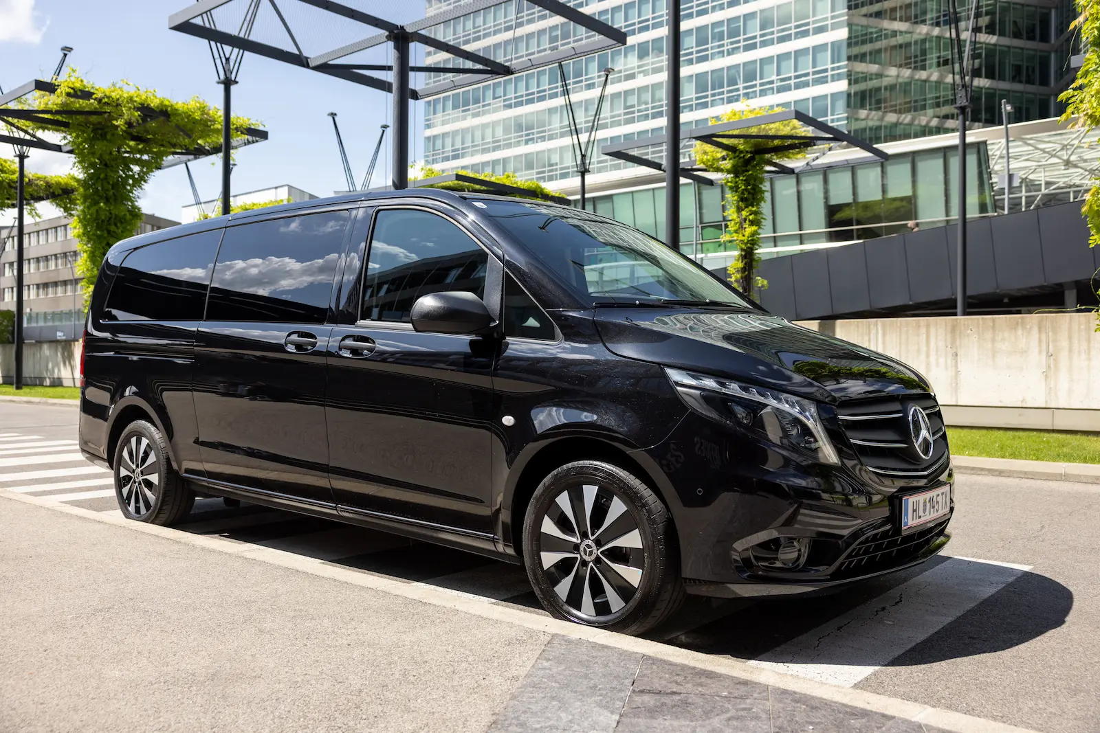 Eleganter Mercedes Benz Van Front Slide in Schwarz vor moderner Stadtarchitektur mit stilvollen Felgen.