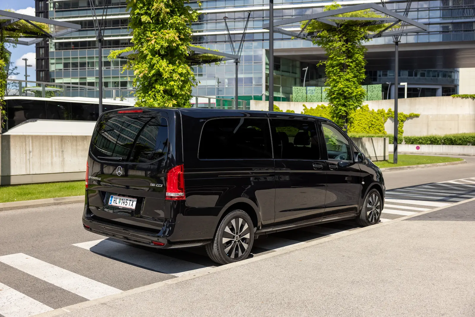 Stilvolle Mercedes Benz Van Rear Slide in Schwarz vor moderner Stadtarchitektur mit eleganten Felgen.