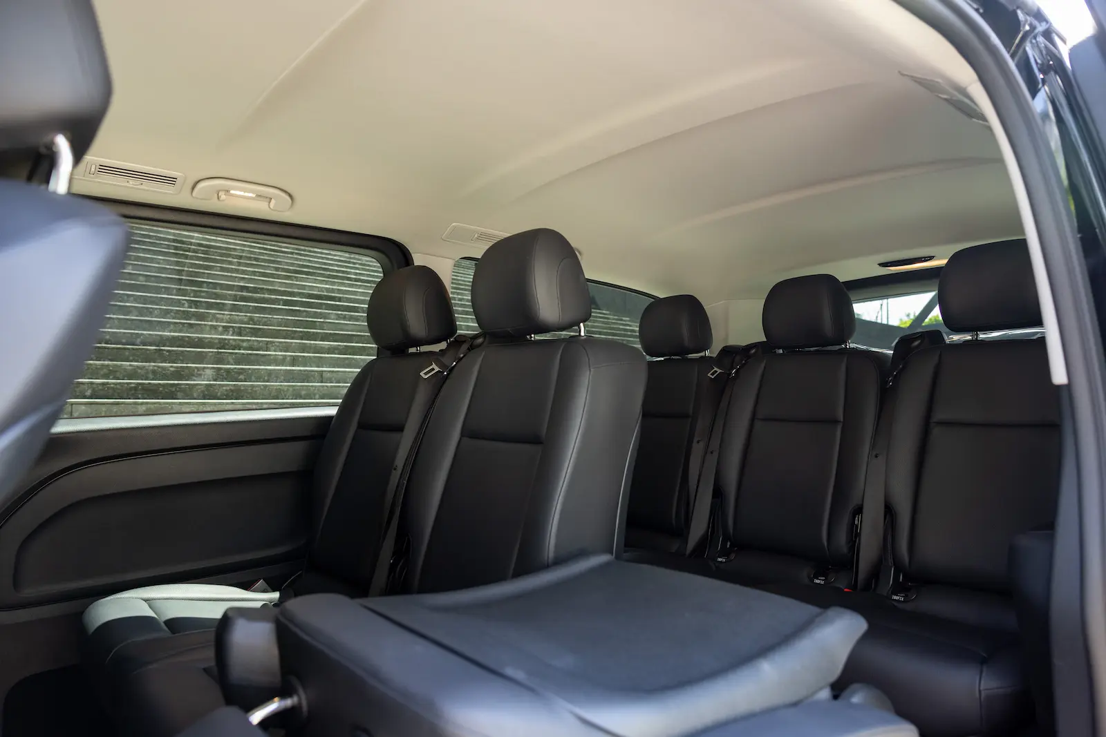 Komfortable Rücksitze eines Mercedes-Benz Vans, Rückansicht von innen mit schwarzen Ledersitzen und moderner Ausstattung.
