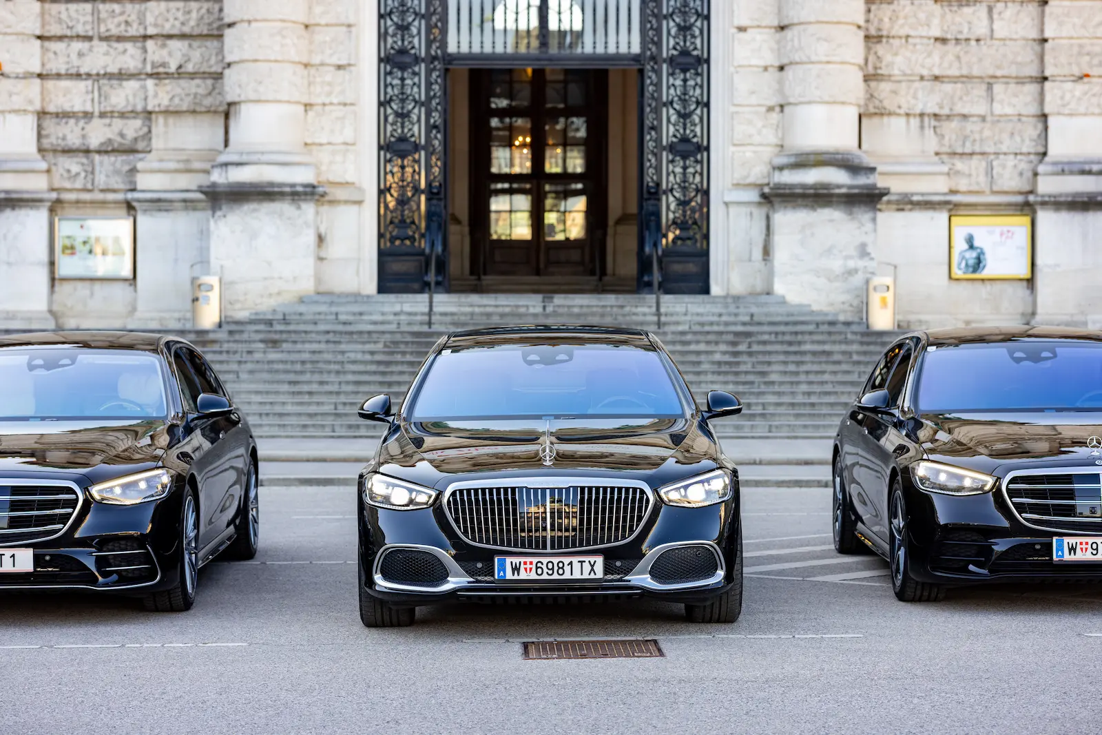 Drei elegante Limousinen für VIP Fahrservice, geparkt vor einem historischen Gebäude mit Treppe und Eingang.