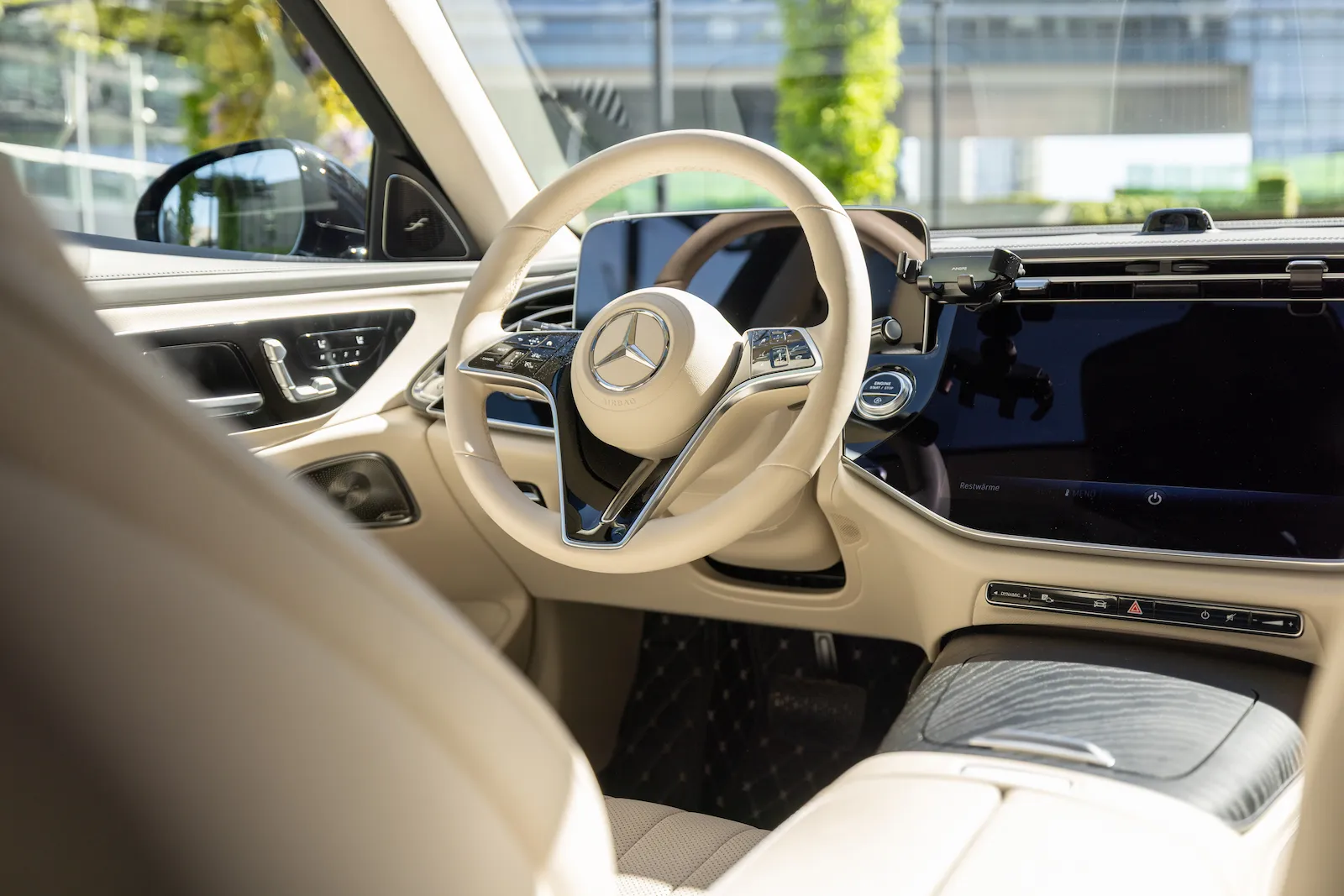 Der luxuriöse Innenraum der MB S-Klasse mit cremefarbenem Lederlenkrad und modernem Touchscreen-Display.