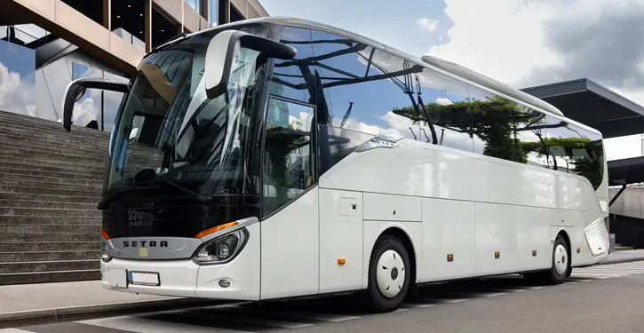 Ein eleganter Setra Front View Bus steht vor einem modernen Gebäude mit Treppen, ideal für Reisen.