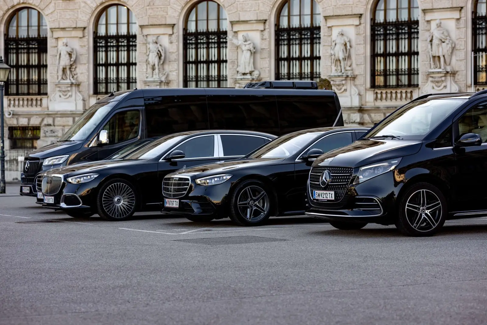Ein eleganter Limousinenservice in Wien mit schwarzen Luxusfahrzeugen vor einem historischen Gebäude, bereit für exklusive Fahrten.